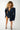 Sustainable dark-wash denim mini dress with long sleeves, cinched waist and structured shoulders.